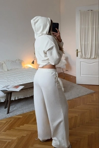 Detail view of cream-colored hooded tracksuit with wide-leg sweatpants and zip hoodie