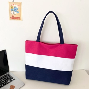 Detail of three-color canvas tote bag featuring pink white and dark blue horizontal stripes