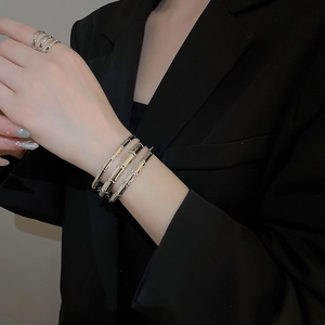 Detail showing high-polished gold tiered bamboo style cuff bracelet and ring set on model