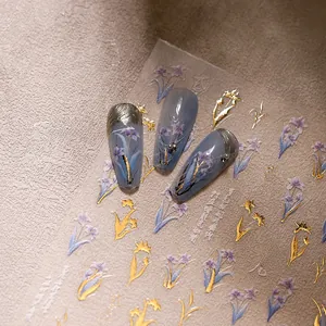 Detailed 5D nail art stickers with purple floral patterns and gold accents on gray nails