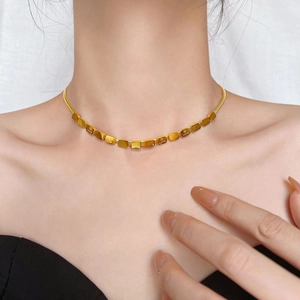 Close-up of gold LOVE square block pendant necklace on model with snake chain detail