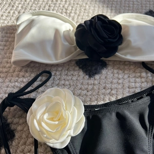 Two-piece black and white bikini set featuring 3D rose details and side tie bottoms