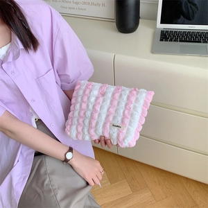 Close-up of portable plush pink and white striped makeup bag with soft texture detail