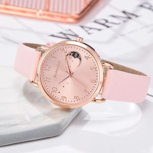 Pink quartz watch with moon pattern dial and rose gold metal case on a soft marble background