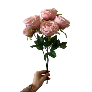Pink silk artificial rose bouquet with five flower heads and green leaves on white background