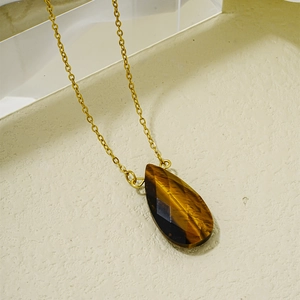 Détail macro du pendentif goutte en œil de tigre facetté sur collier chaîne dorée