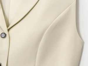 Makro-Detail der beige Weste mit Köperstruktur und strukturierten dunklen Knöpfen