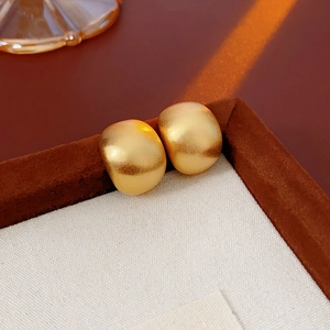 Makroaufnahme matter goldener runder Ohrstecker in einer hochwertigen Schmuck-Geschenkbox