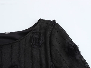 Détail de l'épaule d'une robe noire en maille ajourée avec fleurs 3D appliquées