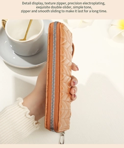 Detail of orange quilted leather wallet showing the smooth silver zipper and stitching