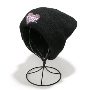 Detalle de un gorro de punto negro de invierno con bordado de corazón rosa y texto
