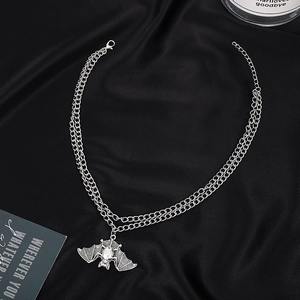 Gothic multilayer bat necklace in silver finish with white gemstone on black silk background