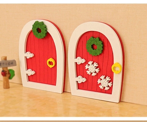 Detailed view of red dollhouse doors with green wreaths and white snowflake patterns