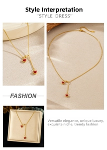 Detail of gold necklace with red heart pendants featuring asymmetric chain tassels