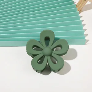 Macro shot of matte forest green flower claw clip on textured pleated paper