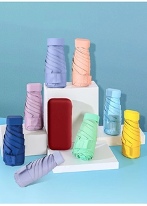 Array of colorful mini capsule umbrellas in various vibrant shades on white display blocks