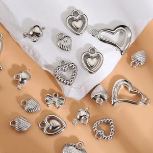 Silver heart pendants and Y2K charms for DIY jewelry making on stone background