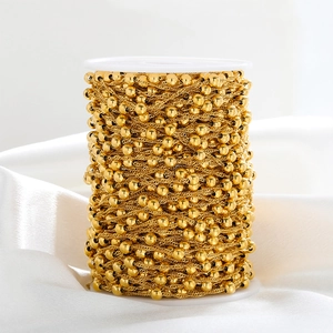 Macro shot of golden stainless steel water wave bead chain wound on white plastic spool