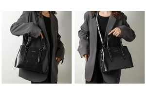 Detail of black faux leather handbag with white text print and twin round handles