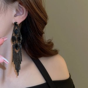 Close-up of black teardrop rhinestone tassel earrings worn by a model in a retro style