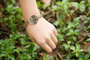 Detail of silver Hamsa Hand pendant bracelet worn by a model in a natural outdoor setting