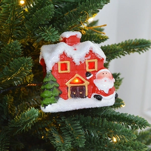 Lighted ceramic Christmas house ornament with Santa Claus hanging on a green tree