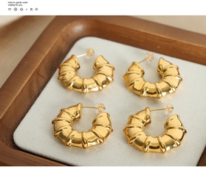 Detailed view of 18k gold plated C-shaped bamboo texture earrings in a jewelry tray