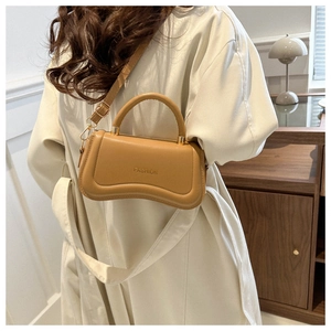 Detail of khaki leather shoulder bag with FASHION embossing worn over a beige coat