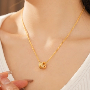 Detail of 18k gold plated cylinder pendant necklace with sparkling cubic zirconia on model