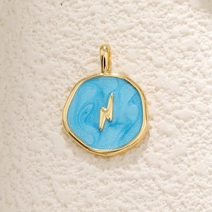 Macro detail of golden lightning bolt pendant with light blue glitter inlay finish