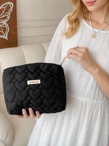 Elegant black heart quilted cosmetic bag featuring soft padded fabric and zip closure