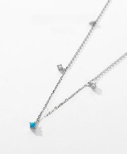 Detailed close-up of silver necklace with turquoise beads and square clear crystals