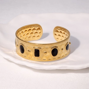Vintage 18K gold plated wide cuff bracelet with black gemstones on a white tray