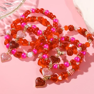 Detail of pink and red beaded heart bracelet with gold charm on pink background