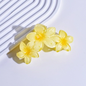 Close-up of yellow floral matte acrylic hair claw clip on a textured display
