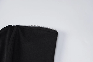 Close-up of black V-neck top showing silver rhinestone trim and fine stitching detail