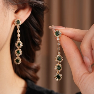 Elegante Goldohrringe mit grünem Edelstein und weißen Diamantblumen-Quasten im Detail
