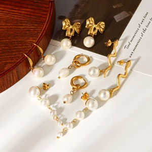 Vue à plat de boucles d'oreilles vintage en perles et acier plaqué or 18k sur plateau