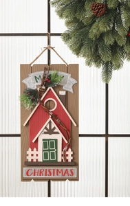 Dettaglio casa di Natale in legno con rami di pino e scritta Merry Christmas incisa