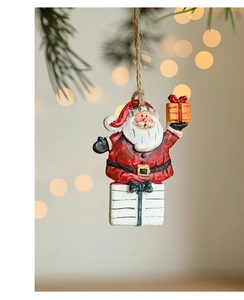 Detailed view of a hand-painted resin Santa Claus ornament hanging on a pine tree