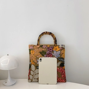 Linen handbag with flower embroidery, sequins, bamboo handle, and tablet for size reference