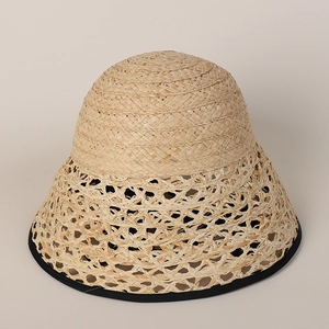Detailed close-up of hollow woven raffia sun hat brim with black ribbon trim finish