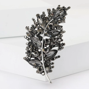 Elegant leaf brooch with charcoal crystals and silver base on a white minimalist platform