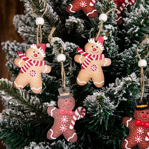Detailed view of gingerbread man wooden ornaments hanging on a snowy Christmas tree