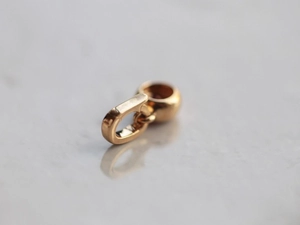 Macro shot of polished gold metal pendant charm with circular design on marble background