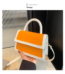 Detail view of orange and white contrast synthetic leather handbag with gold buckle