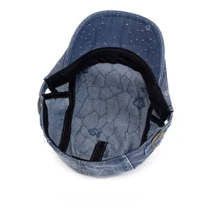 Detail of blue denim newsboy hat interior with floral pattern and adjustable buckle
