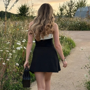 Rear view of black and white color block strapless mini dress on a path during sunset