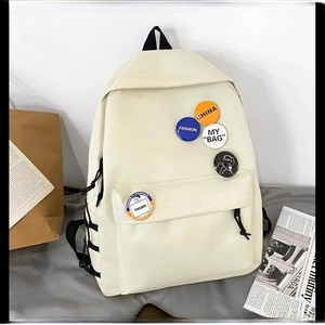 Minimalist off-white canvas backpack with stylish fashion badges on a neutral background