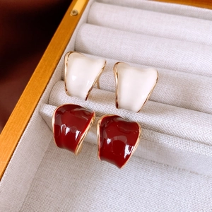 Detail view of gold-plated C-shaped earrings in white and burgundy enamel